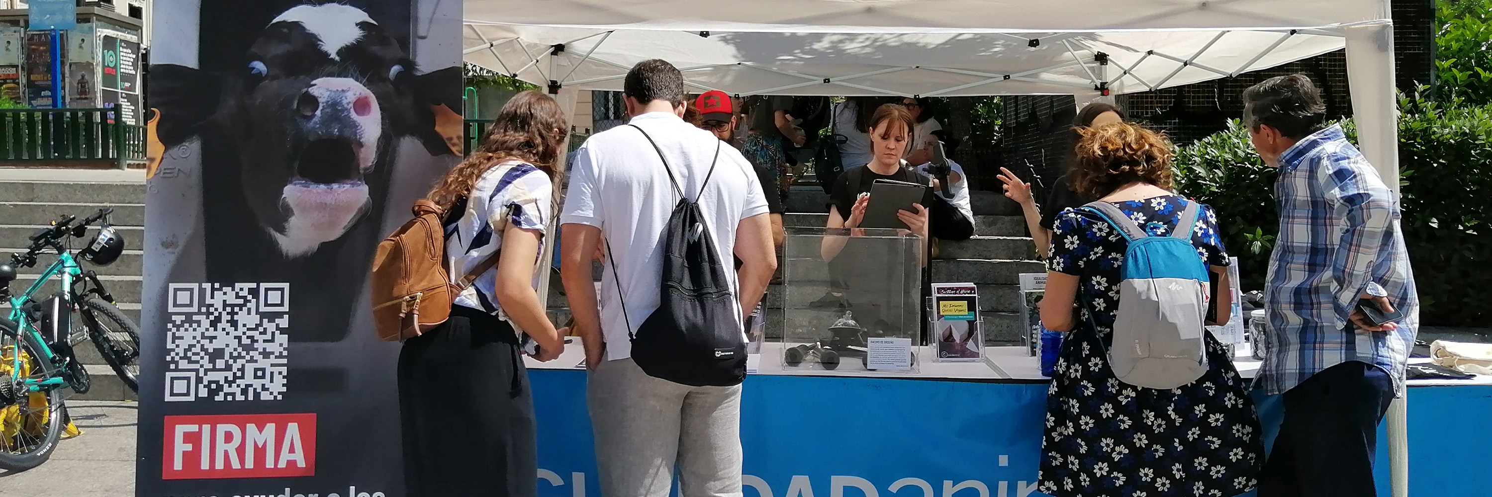 Varias personas miran la mesa informativa de Igualdad Animal
